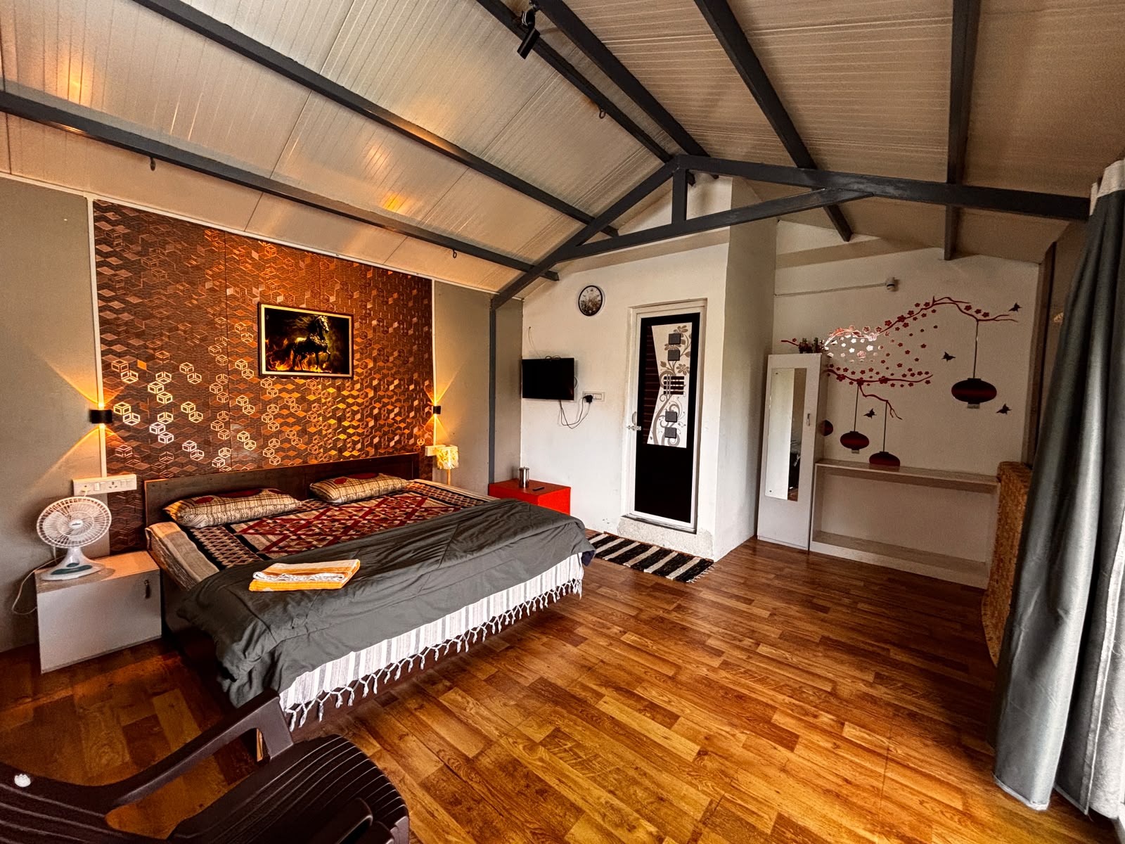 Clean, well-maintained bedroom with pitched roof and wooden floor at MG Homestay